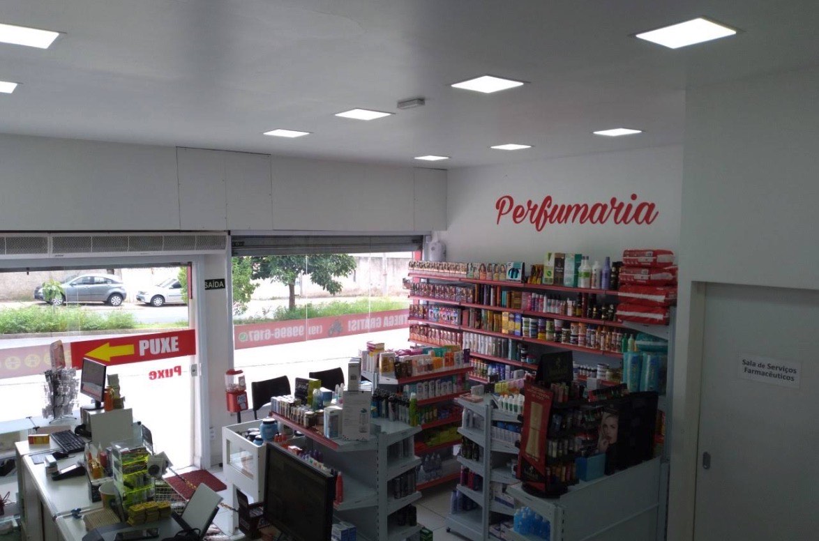 Balcão de atendimento e seção de perfumaria da Droga Popular, com a sala de serviços farmacêuticos ao fundo